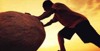 hombre empujando una piedra grande